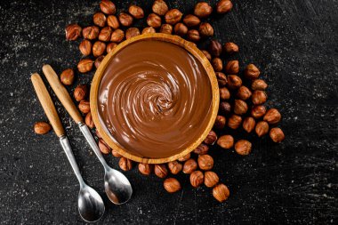 Hazelnut butter in a wooden plate. On a black background. High quality photo