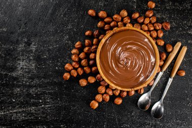 Hazelnut butter in a wooden plate. On a black background. High quality photo