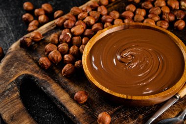 Hazelnut butter on a cutting board with a spoon. On a black background. High quality photo