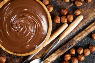 Hazelnut butter on a cutting board with a spoon. On a black background. High quality photo