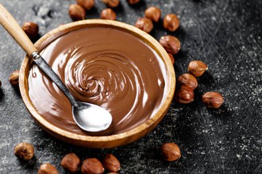 Hazelnut butter in a plate with a spoon. On a black background. High quality photo