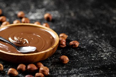 Hazelnut butter in a plate with a spoon. On a black background. High quality photo