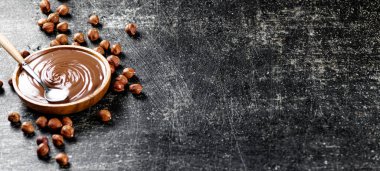 Hazelnut butter in a plate with a spoon. On a black background. High quality photo