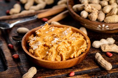 Peanut butter and inshell peanuts on a cutting board. Against a dark background. High quality photo