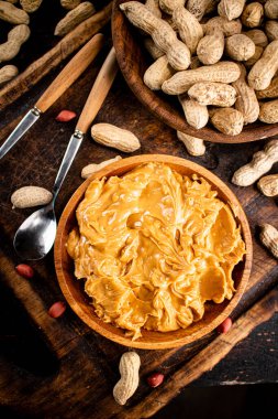 Peanut butter and inshell peanuts on a cutting board. Against a dark background. High quality photo
