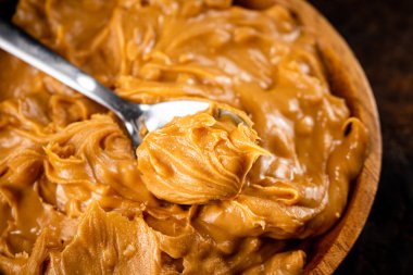 A plate of peanut butter on the table. On a rustic dark background. High quality photo