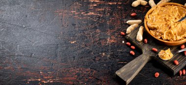 Peanut butter on a plate with a spoon. On a rustic dark background. High quality photo