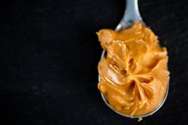 A spoonful full of peanut butter. On a black background. High quality photo