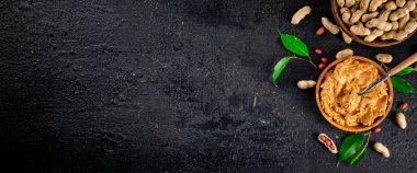 Peanut butter in a wooden plate. On a black background. High quality photo