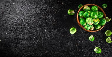 Brussels sprouts in a wooden bowl. On a black background. High quality photo