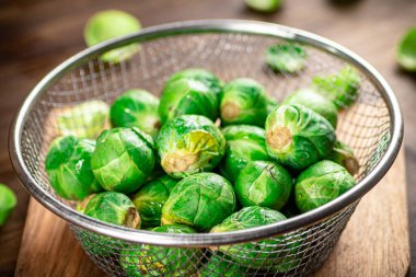 Brussel cabbage in a colander on a cutting board. On a wooden background. High quality photo