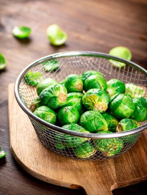 Brussel cabbage in a colander on a cutting board. On a wooden background. High quality photo