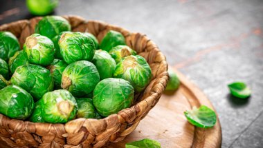 Brussel cabbage in a basket on a cutting board. Against a dark background. High quality photo