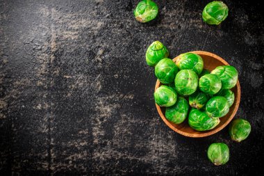 Fresh Brussels cabbage in a wooden plate. On a black background. High quality photo