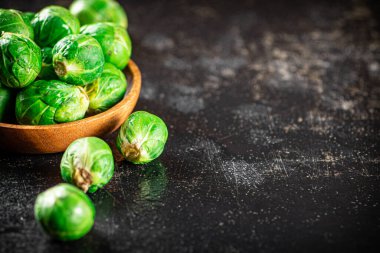 Fresh Brussels cabbage in a wooden plate. On a black background. High quality photo