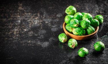 Fresh Brussels cabbage in a wooden plate. On a black background. High quality photo