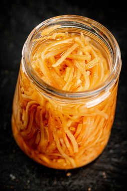 A glass jar with canned carrots. On a black background. High quality photo