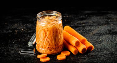 A glass jar with canned carrots. On a black background. High quality photo