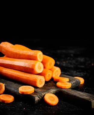 Fresh carrots on a cutting board. On a black background. High quality photo