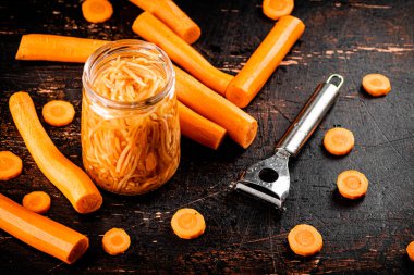 Canned carrots in a glass jar on the table. Against a dark background. High quality photo
