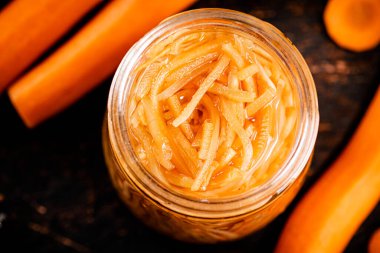 Canned carrots in a glass jar on the table. Against a dark background. High quality photo