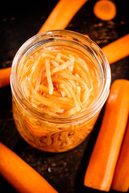 Canned carrots in a glass jar on the table. Against a dark background. High quality photo
