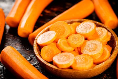 Round pieces of fresh carrots on a wooden plate. Against a dark background. High quality photo