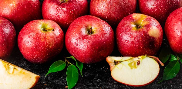 Half and whole apples with leaves on the table. On a black background. High quality photo