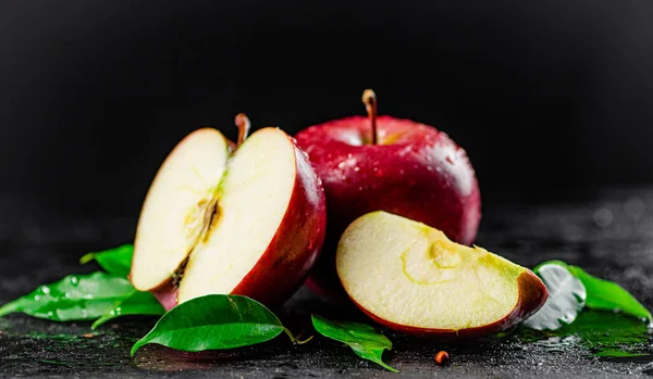 Half and whole apples with leaves on the table. On a black background. High quality photo