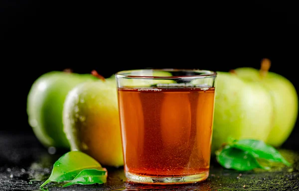 stock image A glass of green apple juice with leaves on the table. On a black background. High quality photo