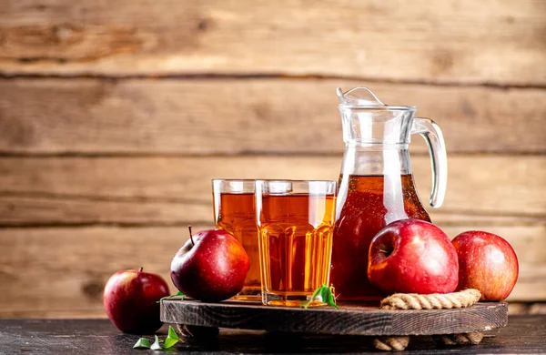 Juice from ripe red apples on tray. On a wooden background. High quality photo