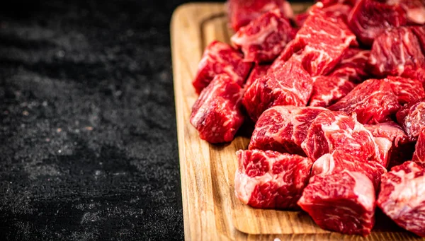 Raw pieces of beef on a wooden cutting board. On a black background. High quality photo