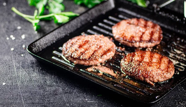 Grilled burger in a frying pan. On a black background. High quality photo