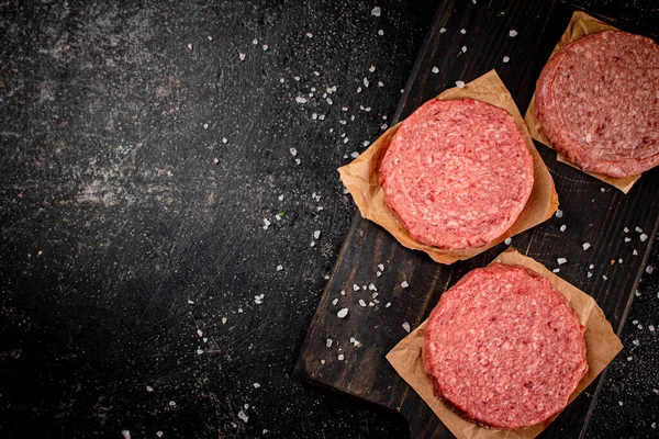 Raw burger on a cutting board. On a black background. High quality photo