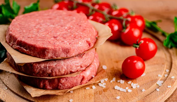 Raw burger with tomatoes. On a wooden background. High quality photo