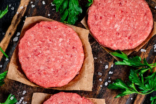 Raw burger on a cutting board with parsley and salt. Macro background. High quality photo