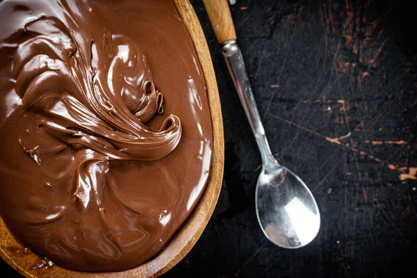 Hazelnut butter in a plate with a spoon. Against a dark background. Top view. High quality photo