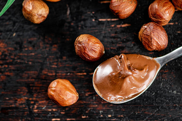 Hazelnut butter in a spoon on the table. On a rustic dark background. High quality photo