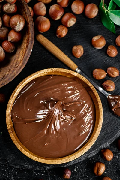 Hazelnut butter on a stone board on a plate and in a spoon. On a black background. High quality photo