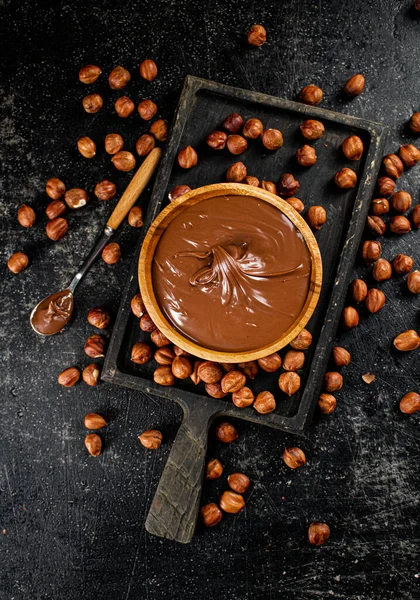 Hazelnut butter on a cutting board with a spoon. On a black background. High quality photo