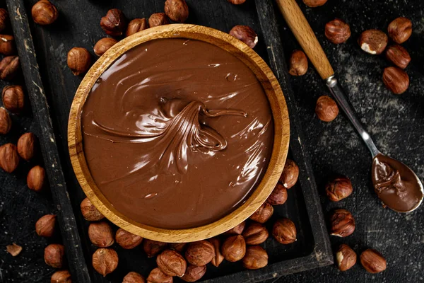 Hazelnut butter on a cutting board with a spoon. On a black background. High quality photo