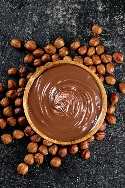 Hazelnut butter in a wooden plate. On a black background. High quality photo