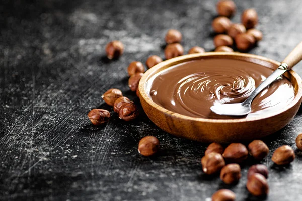 Hazelnut butter in a plate with a spoon. On a black background. High quality photo