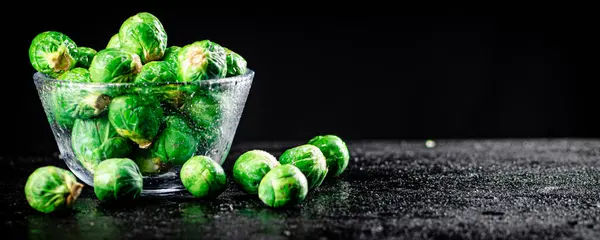 Fresh Brussels cabbage in a glass bowl. On a black background. High quality photo