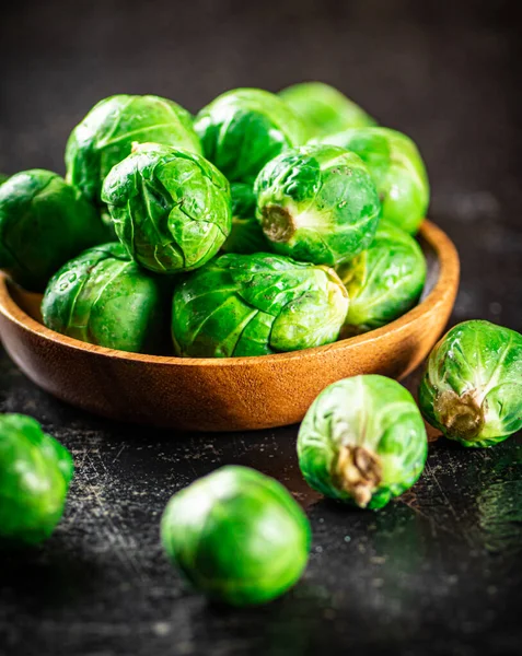 stock image Fresh Brussels cabbage in a wooden plate. On a black background. High quality photo