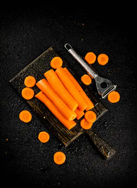 Fresh carrots on a cutting board. On a black background. High quality photo