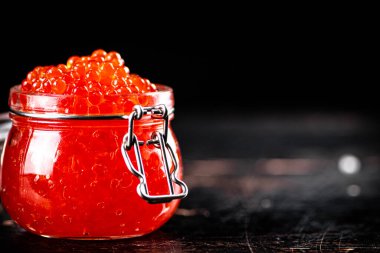 Delicious red caviar in a glass jar. Against a dark background. High quality photo