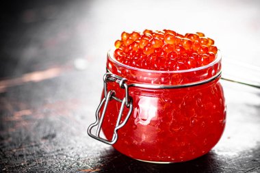 Delicious red caviar in a glass jar. Against a dark background. High quality photo