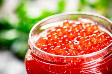 An open jar of red caviar with greens. On a rustic background. High quality photo
