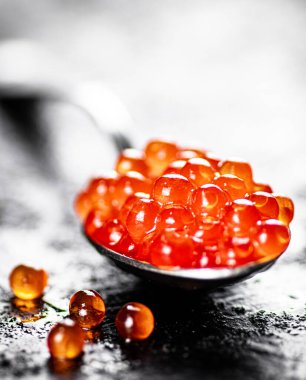 Red caviar in a spoon on the table. On a black background. High quality photo